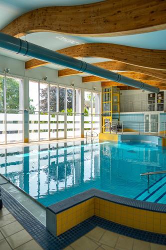 a large indoor swimming pool with blue water at Albatros Medical SPA in Mielno