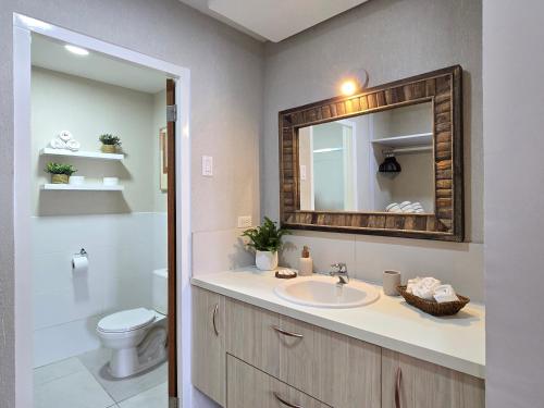 Un baño con lavabo, inodoro y espejo. en Rooi Santo Residence, en Palm-Eagle Beach