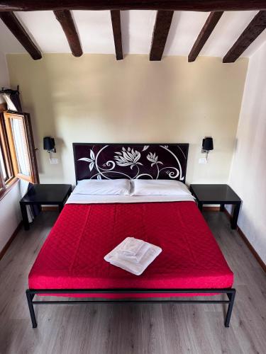 a red bed in a room with two tables at Villa Cittadella in Mantova