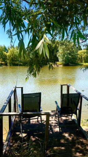 two chairs and a table in front of a lake at Комплекс відпочинку "Садиба БЕРЕЗИНО" in Vinnytsya
