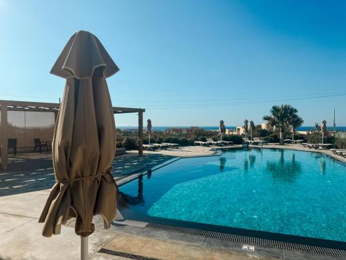 a large swimming pool with an umbrella next to it at La Rêve Luxury Apartments in Hersonissos