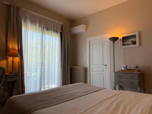a bedroom with a bed and a large window at Hotel des Pins in Soulac-sur-Mer