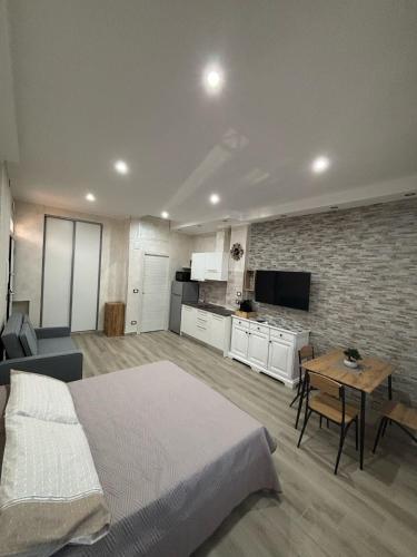 a bedroom with a bed and a table and a kitchen at Ohana Dream House in Alghero