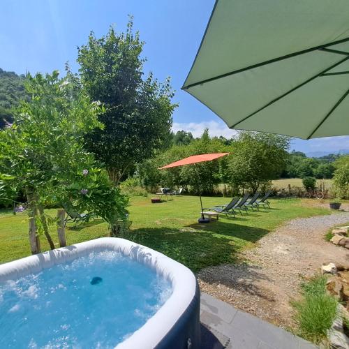 a hot tub in a garden with an umbrella at Gîte Coume a Case, Pyrénées Atlantiques in Lys