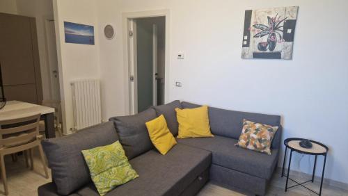 a living room with a gray couch with yellow pillows at Casa Morena in Montecarlo
