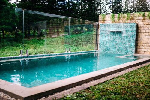 a swimming pool with a glass fence around it at Avas Blue Tagaytay Vacation House with Pool in Kaybagal
