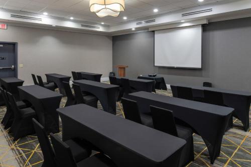 a conference room with black tables and chairs and a screen at Holiday Inn Rock Hill by IHG in Rock Hill