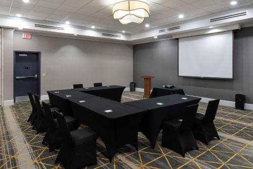 a conference room with black tables and chairs and a screen at Holiday Inn Rock Hill by IHG in Rock Hill