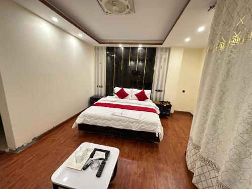 a bedroom with a bed and a table in it at Decent Luxury Hotel Hunza in Alīābād