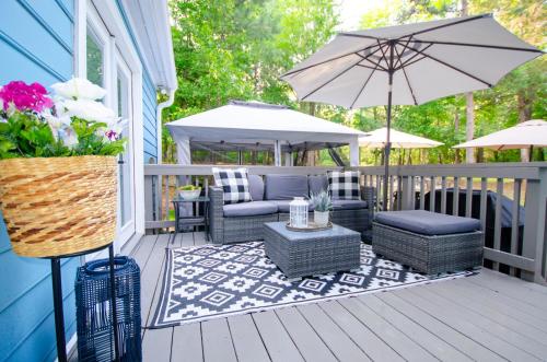 a deck with a patio furniture and an umbrella at Private 1 Acre Retreat, Spa, Firepit, Gym, Chickens, King Suite, Pets in Wake Forest