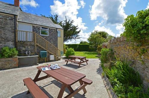 a picnic table and benches in front of a house at The Laurels Holiday Park & Cottages nr Padstow and Wadebridge in Wadebridge