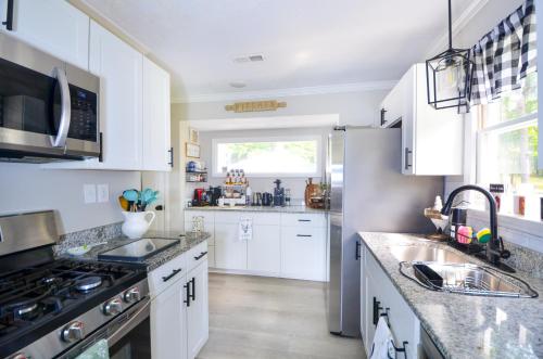 a kitchen with white cabinets and a sink and a stove at Private 1 Acre Retreat, Spa, Firepit, Gym, Chickens, King Suite, Pets in Wake Forest