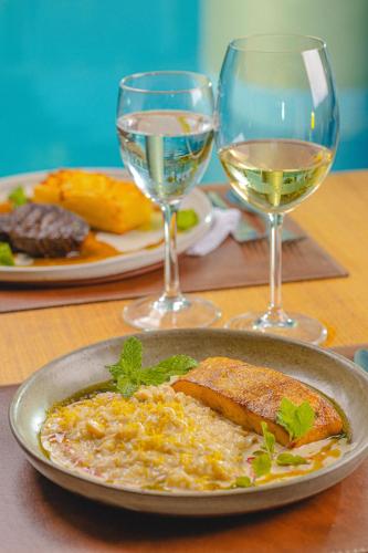 a plate of food on a table with glasses of wine at Verdegreen Hotel in João Pessoa