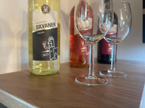 two wine glasses and a bottle of wine on a table at Ferienzimmer Moller in Kolitzheim