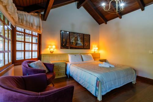 a bedroom with a bed and two chairs at Rosa Casa Jardim da Serra in Canela