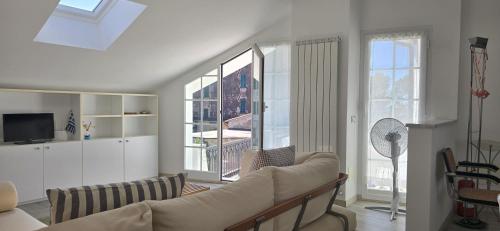 Una sala de estar con un sofá y algunas ventanas. en Villa Rocca - mansarda, en Borgio Verezzi
