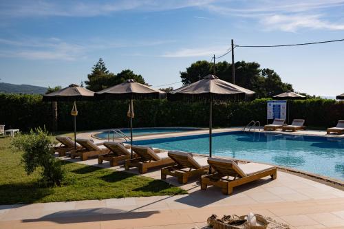 a swimming pool with lounge chairs and umbrellas at Restia in Almiros Beach