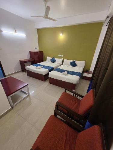 a hotel room with two beds and a chair at Sulthan Hotel & Restaurant in Cochin