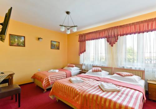 two beds in a room with yellow walls and windows at Hotel Dukat in Biała Podlaska