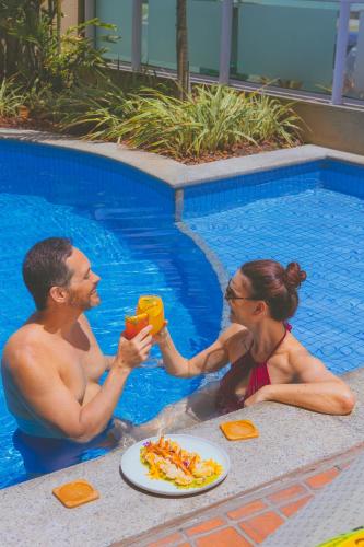 a man and a woman eating pizza in a swimming pool at Verdegreen Hotel in João Pessoa