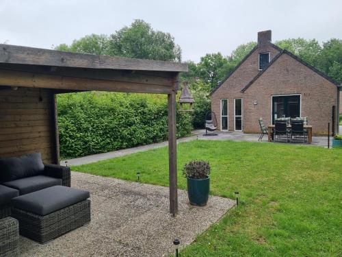 a patio with a couch under a pavilion in a yard at Vrijstaande woning met jacuzzi in grote tuin in Ewijk
