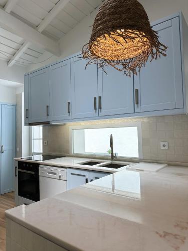 a kitchen with white cabinets and a sink and a chandelier at Casas do Largo- Primavera in Estremoz