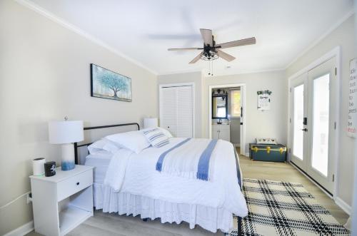 a white bedroom with a bed and a ceiling fan at Private 1 Acre Retreat, Spa, Firepit, Gym, Chickens, King Suite, Pets in Wake Forest