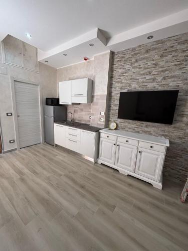 a large kitchen with white cabinets and a flat screen tv at Ohana Dream House in Alghero