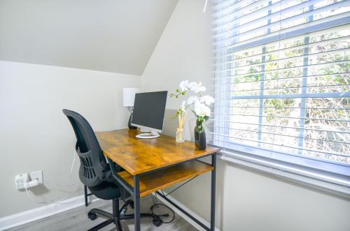 a desk with a computer in a room with a window at Private 1 Acre Retreat, Spa, Firepit, Gym, Chickens, King Suite, Pets in Wake Forest