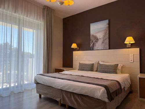 a bedroom with a large bed and a large window at Hotel des Pins in Soulac-sur-Mer
