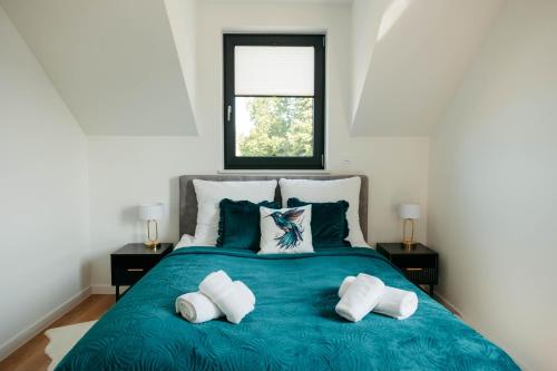 a bedroom with a blue bed with two pillows at Apartamenty Labuda in Garcz