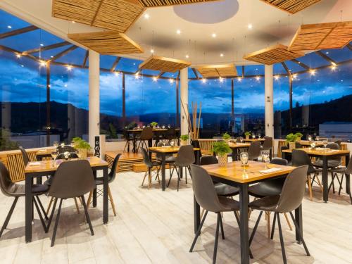 a restaurant with tables and chairs and windows at Hotel Alma in Villa de Leyva