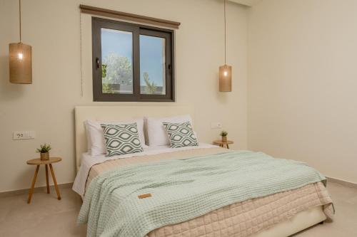 a white bedroom with a large bed with a window at Petra Natura Villa in Zakynthos Town