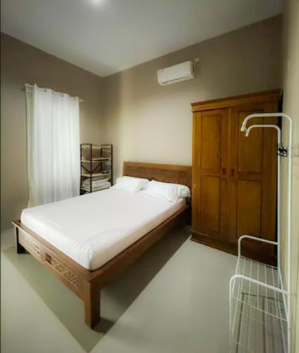 a bedroom with a bed and a wooden cabinet at Villa Cijeruk i1 - View Gunung Salak in Cihideung