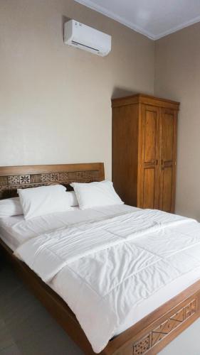 a bedroom with a large white bed with a wooden headboard at Villa Cijeruk i1 - View Gunung Salak in Cihideung