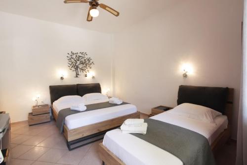 a room with two beds and a ceiling fan at SKYROS AVRA Residences in Skiros