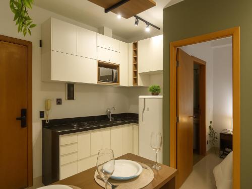a kitchen with white cabinets and a table with wine glasses at Apê super charmoso! Ar-condicionado e piscina in Brasilia