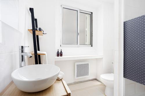 une salle de bain blanche avec un lavabo et une fenêtre dans l'établissement Center Paris République Appartment, à Paris