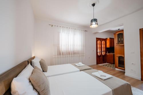 a bedroom with a large white bed and a kitchen at Villa Yucca in Vlorë