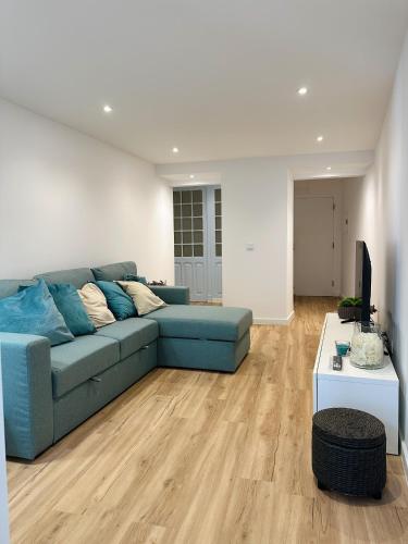 a living room with a blue couch and a television at Casas do Largo- Primavera in Estremoz