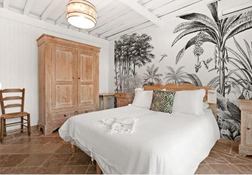 - une chambre avec un lit blanc orné d'une fresque murale dans l'établissement Villa Paradis, aux Issambres