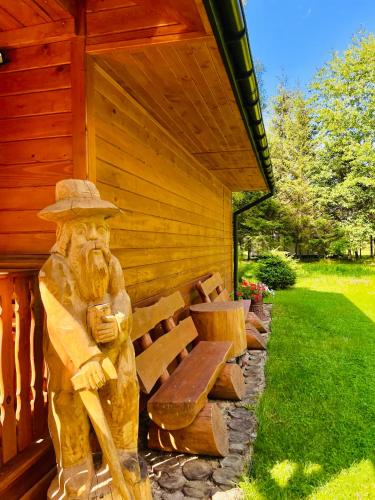 una estatua de un hombre sentado en un banco junto a un edificio en Domek Nida, en Polańczyk