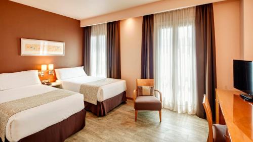 a hotel room with two beds and a television at Sercotel Alcalá 611 in Madrid