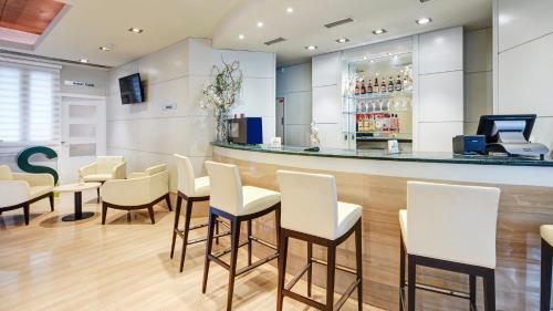 a restaurant with white chairs and a bar at Sercotel Alcalá 611 in Madrid