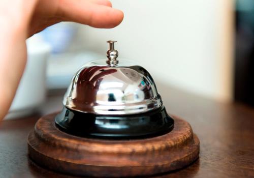a hand holding a bell on a wooden table at Hotel Dukat in Biała Podlaska