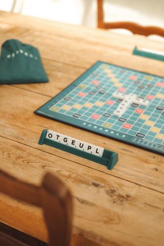 a wooden table with a monopoly board on it at Hôtel Les Voisins Beaucemaine in Ploufragan