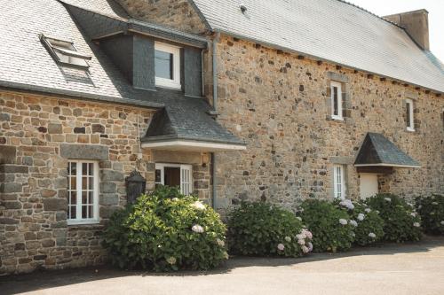 a brick house with bushes in front of it at Hôtel Les Voisins Beaucemaine in Ploufragan