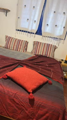 a bed with a red comforter and two pillows at Tigmi Blue - Imsouane Surf et Océan in Imsouane