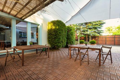 a patio with two wooden tables and chairs on a brick patio at Harry nie z tej bajki & Bałtycka44 Apartments in Olsztyn