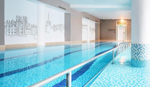 a large swimming pool with blue tiles on the floor at The Caledonian Edinburgh, Curio Collection by Hilton in Edinburgh